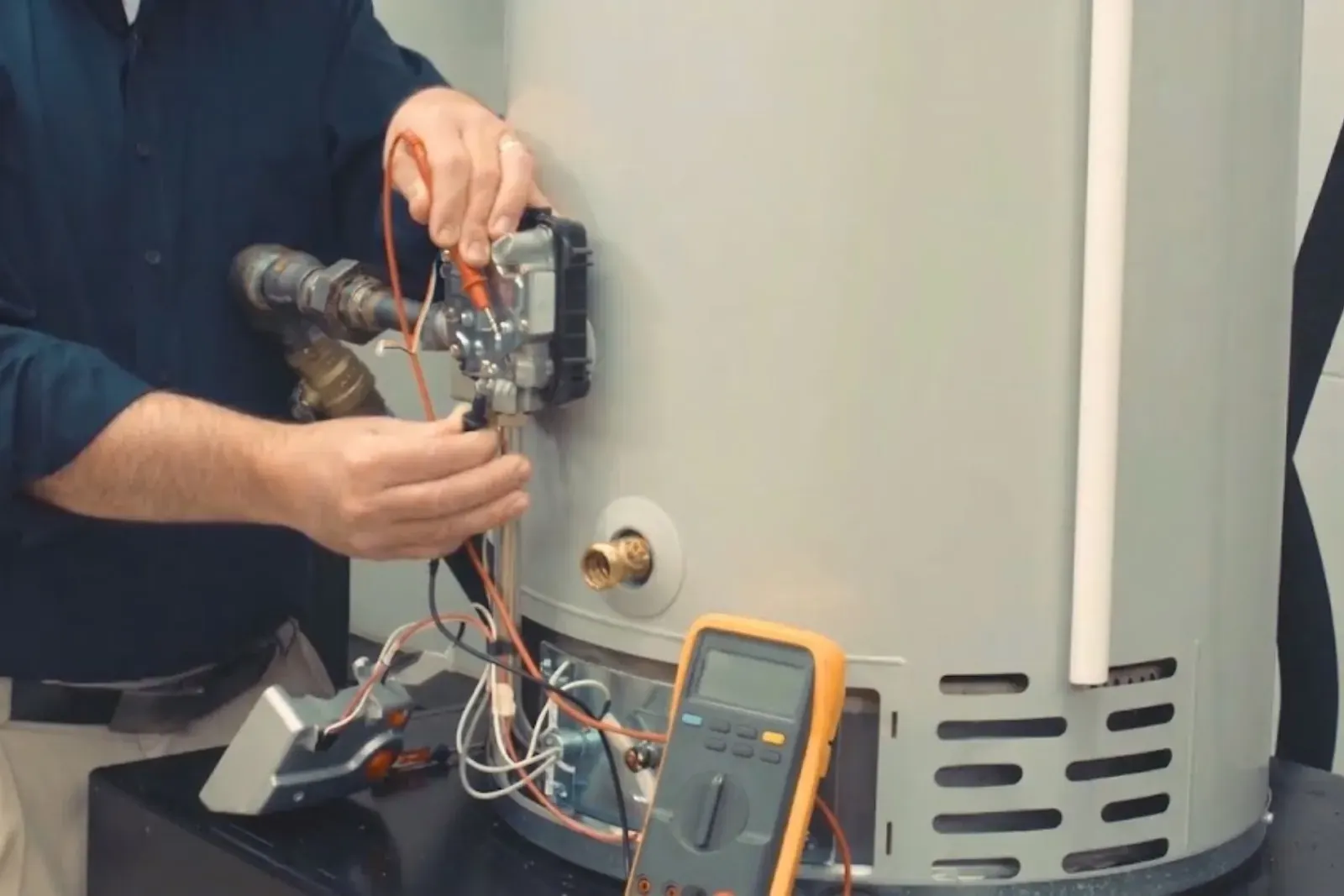 Technician testing the controls of a gas water heater with a multimeter
